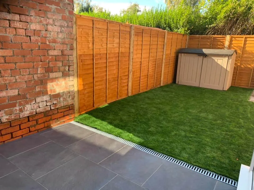 a backyard with a brick wall and a green lawn