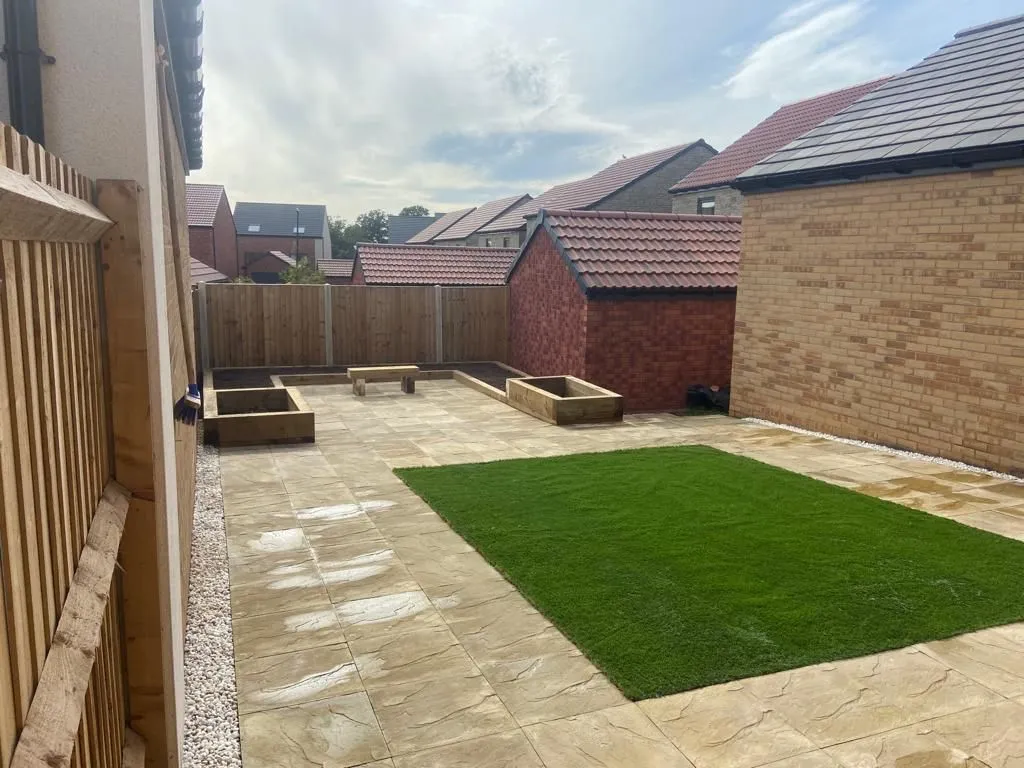 a backyard with a green lawn and a wooden fence